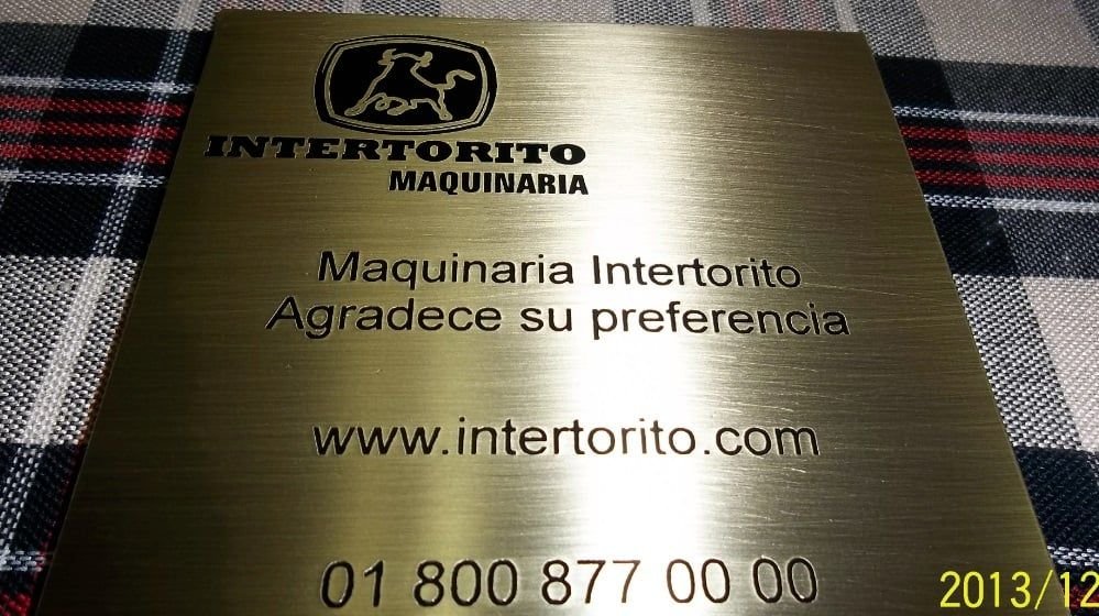 Placa grabada en latón dorado con textos en negro